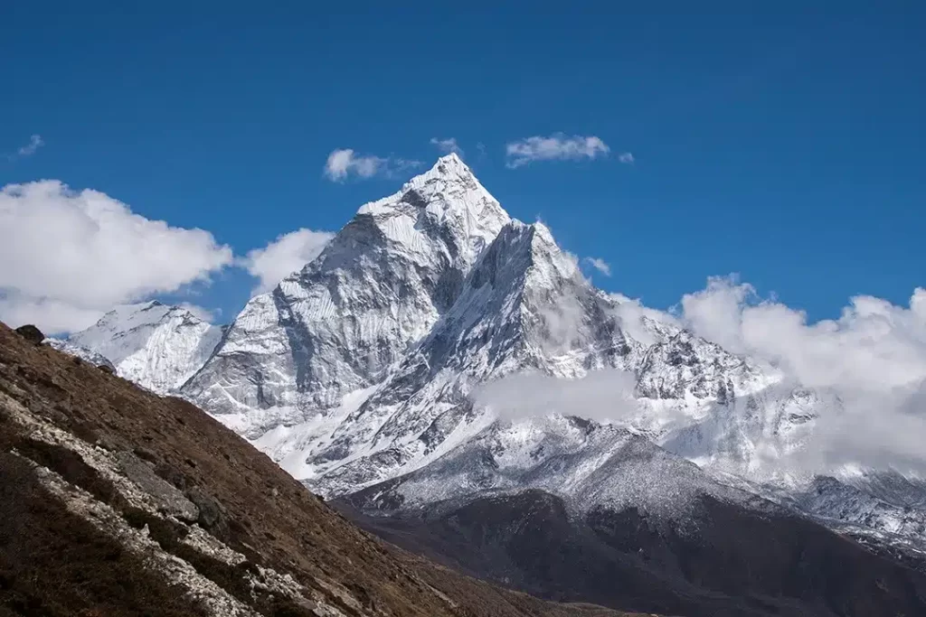 Itinerario de 12 días del campamento base del Everest El campamento base del Everest es un lugar mágico en la tierra. No solo es el sitio más cercano a la montaña más grande del mundo, sino que llegar allí les da a las personas una perspectiva completamente nueva de la vida. El Monte Everest siempre ha sido objeto de fascinación para los amantes de la aventura y los montañistas de todo el mundo. Es por eso que el campamento base del Everest es un sitio de trekking tan popular en Nepal y en el mundo. Para llegar al campamento base del Everest, los turistas requieren al menos nueve días. Requieren una inmensa forma física y energía para completar esta gloriosa expedición. A pesar del terreno desafiante y los alojamientos incómodos, los turistas acuden en masa de todo el mundo para participar en el Everest Base Camp Trek. Esta caminata de 120 km de largo termina en Kala Patthar y generalmente comienza en Lukla. Tendrás que alcanzar hasta 18,500 pies para llegar al punto más alto de la expedición del campamento base del Everest en Kala Patthar. Tendrás que caminar a través de los fascinantes pueblos y ciudades de Nepal durante aproximadamente doce días para llegar allí. En caso de que no haya caminado a ningún lado durante más de diez días, sería mejor que se salte esta caminata. Esta caminata es solo para aquellos que han caminado por terrenos accidentados anteriormente. En esta caminata, tendrás que escalar grandes altitudes durante días. Incluso es posible que deba quedarse en campamentos en diferentes lugares remotos de la caminata. Pero no se preocupe, en la mayoría de los lugares en la caminata del campamento base del Everest, encontrará casas de té donde podrá quedarse cómodamente durante uno o dos días. Muchos senderistas incluso prolongan la excursión al campo base del Everest a dieciséis o diecinueve días. Puede cubrir otros lugares de la región en estos días adicionales, incluidos los lagos Gokyo o el Parque Nacional Sagarmatha. En caso de que hayas tenido el sueño de toda tu vida de hacer un trekking al campamento base del Everest, esta guía te será muy útil. Aquí, obtendrá los detalles importantes y el itinerario detallado de Everest Base Camp Trek. Entonces, ¡comencemos con la aventura de nuestra vida ahora mismo! Formas de llegar al punto de partida de la caminata Para llegar al Campamento Base del Everest, tendrás que recorrer muchos sitios en la región de Solu Khumbu. Para llegar allí, tendrás que llegar a Lukla. Lukla es una ciudad importante en la región de Khumbu en Nepal. Hay varias formas de llegar a Lukla, pero la más común es tomar un vuelo. El aeropuerto de Lukla es uno de los aeropuertos más famosos del país. Se puede llegar fácilmente tomando un vuelo desde Katmandú. El trayecto entre Katmandú y Lukla no te llevará más de treinta minutos. Mucha gente también viaja a Lukla en Jeep. Necesitarás más de seis horas para llegar a Lukla desde Katmandú en coche. En caso de que quiera comenzar su caminata desde antes de Lukla, puede llegar a Salleri. Al elegir Salleri como punto de partida de su Everest Base Camp Trek, necesitará cuatro días más para completarlo. El mejor momento para participar en el campamento base del Everest Trek Los excursionistas y montañeros participan en la caminata del campamento base del Everest durante todo el año. Pero sería mejor para ti si eliges las estaciones de primavera u otoño para ir allí. Entre marzo a mayo y finales de septiembre a principios de noviembre, todo el recorrido luce excesivamente hermoso. Además, el clima de la zona de Khumbu durante estos meses es perfecto para la exploración. En la primavera, podrá presenciar los vibrantes rododendros en sus formas completamente florecidas a lo largo de la caminata. Si vas allí en otoño, tendrás una vista nítida del Monte Everest, el Monte Annapurna, el Monte Makalu y otras cadenas montañosas debido al horizonte despejado. A pesar de los puntos positivos de participar en el Everest Base Camp Trek en dichas temporadas, algunos amantes de la naturaleza prefieren evitarlos. Debido a la popularidad de los meses, toda la región que rodea al Everest se llena de gente en ese momento. Es por eso que muchas personas prefieren participar en esta caminata fuera de temporada. Realmente pueden completar el viaje en soledad durante la temporada baja. El itinerario perfecto de 12 días para el campamento base del Everest Para comenzar el siempre famoso Everest Base Camp Trek, primero deberá llegar a Katmandú. Sería mejor para usted si deja libre el primer día en Katmandú para hacer turismo. Fácilmente podría visitar la mayoría de los lugares de renombre del valle en un día. Si es un excursionista experimentado, puede volar a Lukla desde Katmandú solo al día siguiente, o también puede tener el segundo día libre. Ahora, su caminata realmente comienza cuando llega a Lukla. A continuación, obtendrá un itinerario completo de la caminata. Día 1: Trekking a Phakding Lukla es una ciudad bastante popular en Nepal, desde donde comienzan muchas rutas de senderismo populares. Como muchas otras caminatas, la caminata del campamento base del Everest también comienza en Lukla. El primer día de su caminata comenzará con las majestuosas vistas del valle de Dudh Koshi. En este día, tendrá que llegar a Phakding, una pequeña ciudad nepalí con una variedad de casas de té donde los huéspedes pueden pasar la noche cómodamente. La distancia de Lukla a Phakding no es tan larga, pero el terreno empinado puede agotarte fácilmente. Podrás presenciar las hermosas vistas de los picos nevados en medio de la exuberante vegetación de los bosques solo desde este día. El sendero cuesta abajo impactará tus rodillas. Es por eso que una estadía cómoda en Phakding será útil para rejuvenecerlo. Día 2: Trekking a Namche En el segundo día de la caminata del campamento base del Everest, tendrá que caminar hasta Namche Bazaar. La caminata de Phakding a Namche Bazaar es bastante desafiante, ya que tendrás que escalar una altitud de acero para llegar allí. El río Dudh-Koshi lo seguirá a lo largo de su caminata. La belleza circundante del camino realmente te asombrará. Si tiene algunos días adicionales en la mano, puede tomar un desvío y caminar hasta el Parque Nacional Sagarmatha en el camino. De lo contrario, tendrás que seguir moviéndote para llegar a Monjo. Ahora bien, Monjo es el sitio donde tendrás que registrarte como trekker. La última parte de la caminata de Monjo a Namche Bazaar es bastante desafiante. El cambio abrupto de altitud te hará realmente cansado. Es por eso que una noche en Namche Bazaar te hará sentir tan bien. Esta ciudad es bastante moderna y actualizada en comparación con otras ciudades rurales de Nepal. Encontrará tiendas de equipo de trekking, cafés, pubs y muchas tiendas diferentes para todas sus necesidades allí. Los hoteles en Namche Bazaar son los mejores de toda la región de Khumbu. Día 3: Aclimatación en Namche Bazaar Ubicado a una altitud de 11,286 pies, Namche Bazaar es el mejor lugar para aclimatarse. Por eso sería mejor que te quedaras allí una noche más. En el tercer día de su caminata, puede explorar los hermosos sitios de Namche. Durante su estadía allí, siempre intente caminar a altitudes más altas. Al caminar hasta el hospital Khunde, el punto Sunrise, el museo Sherpa Culture y otros, verá y conocerá mucho sobre la región de Khumbu y se aclimatará bastante bien a altitudes más altas. Día 4: Caminata a Tengboche En el cuarto día de la excursión, tendrás que caminar hasta Tengboche. La caminata puede parecer bastante agotadora al principio, pero pronto se sentirá lleno de energía debido a las asombrosas vistas de los alrededores. Después de dejar Namche, las vistas del Himalaya se volverán más claras. Te rejuvenecerás genuinamente al ver las espectaculares vistas de las montañas. Además, podrás vislumbrar el Monte Everest con bastante claridad por primera vez en el viaje. Las vistas seguirán animándote a completar la caminata a Tengboche. Durante este viaje, te encontrarás con diferentes pueblos sherpas donde aprenderás mucho sobre el Monte Everest. Después de caminar durante la mayor parte del día, llegará al monasterio de Tengboche. Este templo budista es el monasterio más grande de toda la región. El sitio de este monasterio con el telón de fondo de las majestuosas montañas realmente lo cautivará. Es mejor explorar este sitio justo después de llegar allí. Día 5: Caminata a Dingboche Después de pasar una noche en una de las casas de té de Tengboche, tendrás que empezar la caminata a Dingboche a la mañana siguiente. Esta caminata es relativamente más fácil ya que es cuesta abajo en su camino. Pero el fuerte descenso podría lastimarte las rodillas. Por lo tanto, trate siempre de moverse lentamente para minimizar la presión sobre las rodillas. En el camino, tendrás que cruzar el hermoso río Imja Khola. También te encontrarás con Pangboche, un hermoso pueblo que ofrece una vista espectacular de Ama Dablam. Poco después de cruzar Pangboche, llegará a Dingboche. Al igual que Tengboche, Dingboche también es un monasterio budista de renombre en Nepal. Este sitio es el monasterio más grande de Khumbu. Como llegará a Dingboche durante el día, tendrá tiempo para explorar el monasterio con bastante facilidad. Las historias que escuchará asociadas con el monasterio realmente lo sorprenderán. Día 6: aclimatación en Dingboche A medida que transcurran los días de su viaje al campamento base del Everest, la altitud aumentará. Necesitarás aclimatarte con la altura para seguir moviéndote. Después de Namche, Dingboche es el segundo lugar de este viaje donde tendrás que pasar un día para aclimatar tu cuerpo. Puede pasar el día relajándose en la región, o puede realizar caminatas más cortas para sentirse cómodo con la región. La parte alta del pueblo es bastante bonita. Muchos senderistas acampan en esta zona del pueblo. Puede caminar para ver Nangan Dzong y Dolma Ri mientras se hospeda en Dingboche. Las vistas panorámicas que presenciará desde Dingboche realmente lo harán feliz de haber venido a este viaje. Día 7: Trekking a Lobuche Después de pasar dos días en Dingboche, ahora es el momento de reiniciar la caminata. En el séptimo día del viaje, caminarás hasta Lobuche. El trekking a Lobuche te dará la oportunidad de caminar por senderos nevados por primera vez en la expedición. A lo largo de la caminata, obtendrá impresionantes vistas de los picos Tawache y Cholatse. Rara vez verá pueblos o casas en este camino debido al clima duro y al terreno complicado. La parte más difícil de toda la caminata se encuentra al pie del glaciar Khumbu. Este glaciar es el más alto del mundo, y escalarlo será sin duda uno de los incidentes más aventureros de tu vida. En este viaje, verá muchos túmulos de piedra dedicados a los recuerdos de los sherpas que murieron en las últimas caminatas por el Everest. Después de seguir el glaciar por un tiempo, finalmente llegarás a un pequeño pueblo conocido como Lobuche, donde pasarás la noche. Día 8: Trekking al Campo Base del Everest Ahora, este es finalmente el día en que llegarás al famoso campamento base del Everest. En el octavo día de la caminata, comenzará su caminata al amanecer desde Lobuche. La vista del Himalaya y todo el valle de Khumbu durante el amanecer te dejará atónito. Podemos garantizar que la vista que encontrará durante esta caminata será sin duda una de las mejores vistas de su vida. Tendrás que seguir caminando por el glaciar Khumbu también este día. Después de caminar durante unas horas, llegará a Gorak Shep. En este sitio se encuentran algunos restaurantes y albergues donde puede comer o tomar un refrigerio ligero. Finalmente, después de una caminata de unas horas desde Gorakshep, llegarás al campamento base del Everest. Cuando llegue al campamento base, se sorprenderá al ver la gran cantidad de grupos presentes allí. Verá varias tiendas de campaña acampadas en el lugar. Después de ir allí, tómese un momento para sumergirse en la belleza del Himalaya y agradezca haber tenido la suerte y estar lo suficientemente en forma para venir a esta caminata. Es posible que se emocione después de llegar a este punto, pero pronto tendrá que regresar a Gorak Shep para pasar la noche. Día 9: Trekking a Kala Patthar Ubicada a una altitud de 18,500 pies, Kala Patthar es la cima de la caminata del campamento base del Everest. Este sitio será el punto principal de su caminata. No todo el mundo sube a la cima, pero aquellos que lo hacen pueden presenciar las majestuosas vistas del hermoso glaciar Khumbu y el Monte Everest. Incluso si no subes a la cima, verás las impresionantes vistas de la región circundante. La mejor parte de Kala Patthar es que se encuentra justo enfrente del Monte Everest. Entonces, llegar a su cima te permitirá comprender la gloria surrealista de la montaña más alta del mundo. Desde la cumbre de Kala Patthar, tendrás que descender un largo camino hasta Lobuche. En caso de que no vayas a escalar Kala Patthar, tendrás que caminar hasta Periche, un pequeño pueblo en Khumbu. Día 10: Trekking a Tengboche El décimo día de su expedición, comenzará su viaje de regreso. Desde Periche o Lobuche, tendrás que caminar para llegar a Tengboche. Si se ha perdido algunos puntos que rodean a Tengboche, incluido Pangboche o el monasterio, puede explorarlos extensamente durante esta caminata. Tendrás todo el día para llegar al pueblo. Por lo tanto, haga clic en tantas imágenes como desee y diviértase de verdad. Día 11: Trekking a Namche En el penúltimo día de la caminata, caminarás hasta Namche Bazaar. El viaje será relativamente mucho más fácil. En el camino, podrá presenciar el río Dudh Koshi con bastante facilidad. Si quieres hacer algunas compras, recuerda hacerlo en Namche Bazaar. Día 12: Trekking a Lukla En el último día de su viaje al campamento base del Everest, caminará hasta Lukla. El viaje realmente te hará sentir nostalgia por los últimos once días que pasaste en medio de la naturaleza salvaje del Himalaya. Pero haga que la última noche en Lukla valga la pena disfrutando de una buena comida con su familia o amigos. El viaje al campamento base del Everest no es nada fácil, pero con pura determinación, se puede lograr. A lo largo del viaje, podrá hospedarse en cómodas casas, además de algunos sitios. Además, la comida que se ofrece en estas casas de té y hoteles es bastante deliciosa. Esta caminata realmente te ayudará a conectarte con la naturaleza en su forma más auténtica. Al estudiar este blog, esperamos que tenga una percepción clara de la caminata al campamento base del Everest.